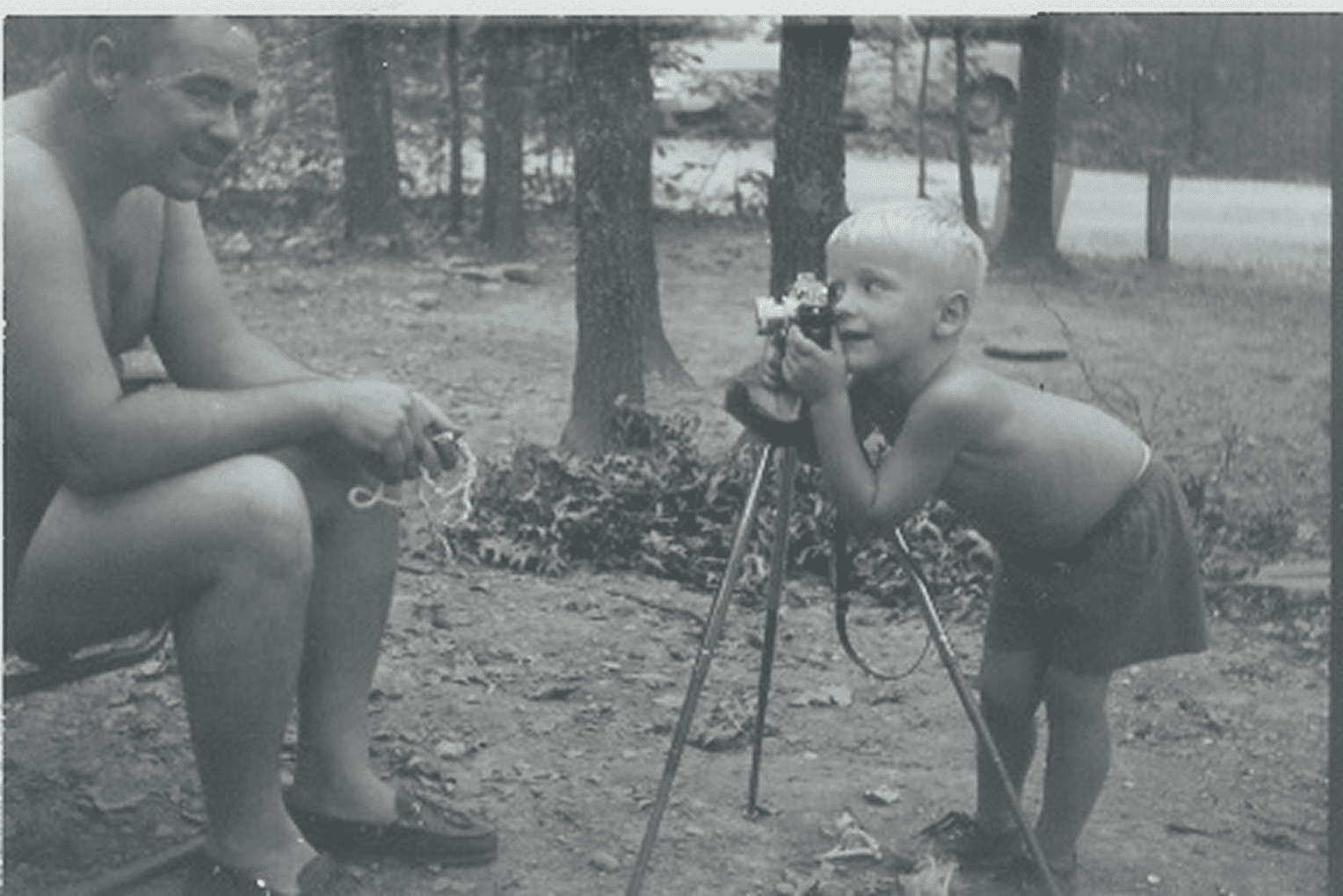 Child photographing man outdoors with camera.