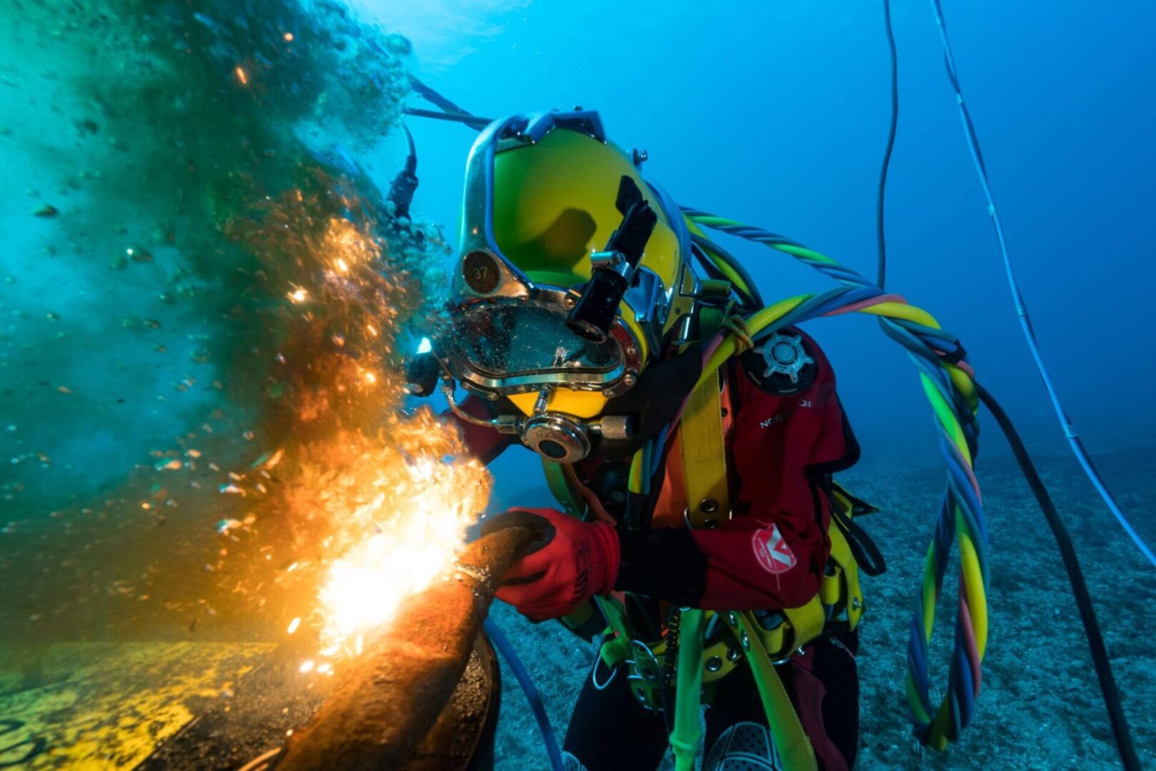 Underwater diver welding with sparks flying.