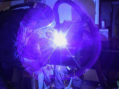 Welder working with bright blue sparks.