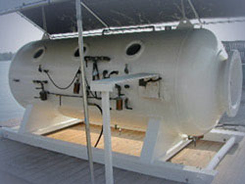 White hyperbaric chamber on wooden platform.