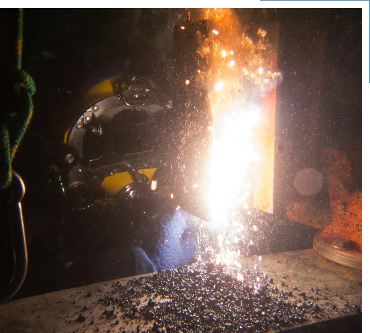 Underwater welding with bright sparks and helmet.