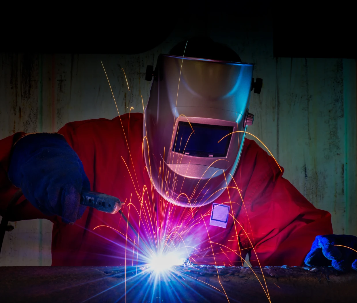 Welder in protective gear with sparks flying.