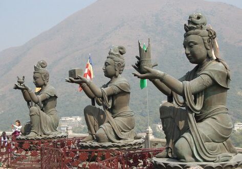 Three statues offering gifts at mountain temple.